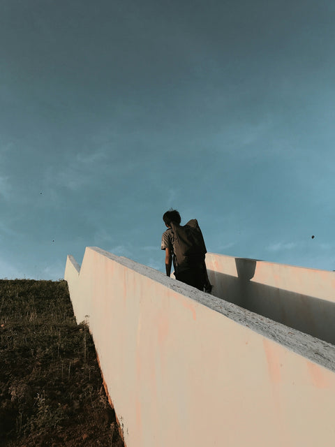 man in black jacket sitting on white concrete wall during daytime
